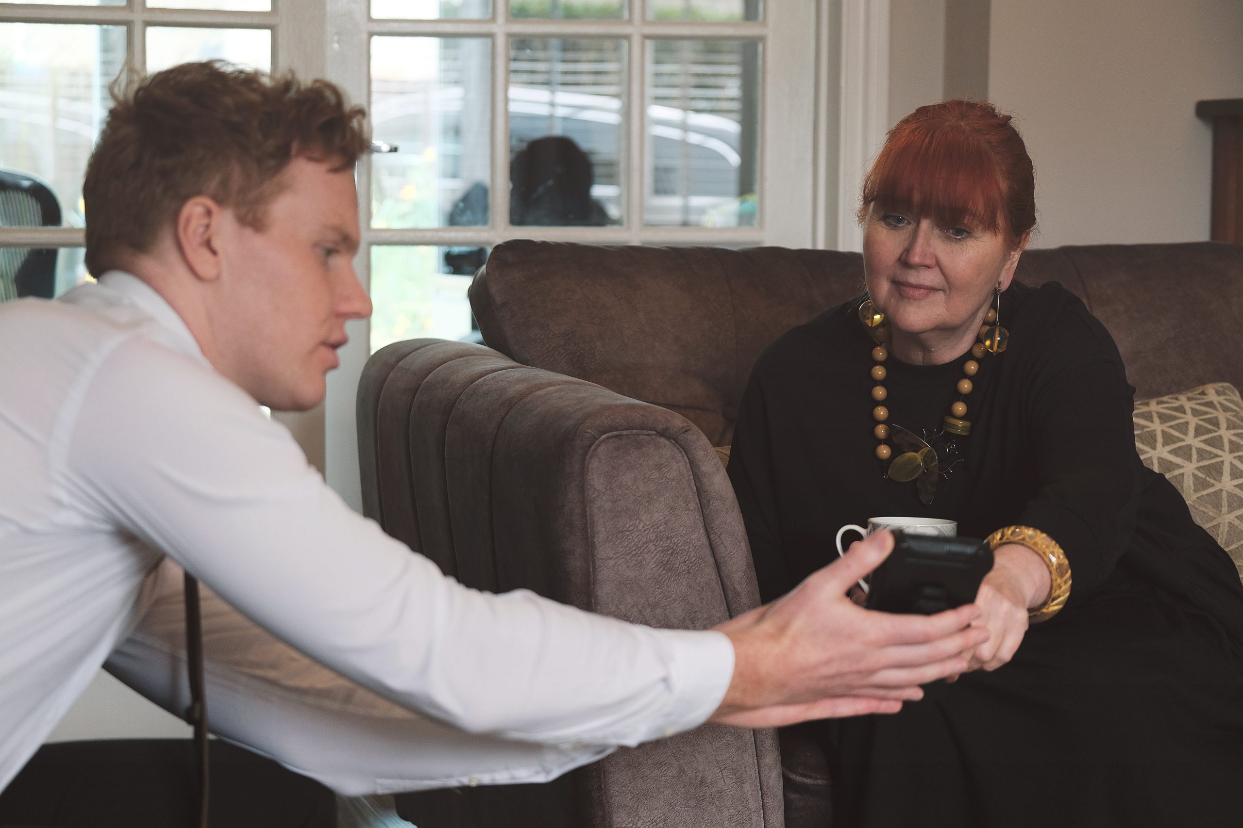 a young professional person providing guidance to another person, who is sat near them on a sofa